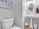 Cozy bathroom with a pedestal sink and modern toilet, featuring an attractive oval mirror and artistic wall decoration at 7212 Avalon Dr, Douglasville, GA 30135