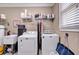 Well-lit laundry room with modern washer and dryer and ample storage space on wire shelving at 7212 Avalon Dr, Douglasville, GA 30135