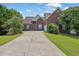Brick home featuring a long driveway, a manicured lawn and mature landscaping at 4591 Millstone Walk Ne Dr, Buford, GA 30519