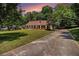 Inviting front exterior with a long driveway, well-kept lawn, traditional brick facade, and warm sunset glow at 1828 Brandy Woods Se Dr, Conyers, GA 30013