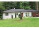Quaint one-story home with a brick exterior, manicured bushes and a lush green lawn at 3175 West Manor Sw Cir, Atlanta, GA 30311