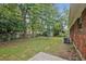 Expansive backyard with mature trees surrounding the brick home for privacy and shade on a sunny day at 622 Sheffield Rd, Norcross, GA 30071