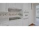 Close-up view of a kitchen featuring modern cooktop, white cabinets, and a tiled backsplash at 622 Sheffield Rd, Norcross, GA 30071