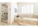 Luxurious bathroom showcasing a soaking tub with tile surround, plantation shutters, and glass shower at 5352 Lacosta Ln, Alpharetta, GA 30022