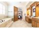 Bright bathroom offering double vanities, tile flooring, a soaking tub, and an open door to bedroom at 5352 Lacosta Ln, Alpharetta, GA 30022