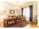 Dining room featuring hardwood floors, elegant chandelier, and window with dark blue curtains at 5352 Lacosta Ln, Alpharetta, GA 30022