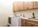 Well-lit laundry room with modern washer and dryer set with upper and lower wooden cabinetry at 5352 Lacosta Ln, Alpharetta, GA 30022