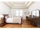 Cozy bedroom featuring a tray ceiling, hardwood floors, and abundant natural light from windows at 5352 Lacosta Ln, Alpharetta, GA 30022