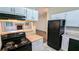 Efficient kitchen featuring black appliances, white cabinets, laminate countertops, and a view of the living room at 5517 Green Wing Ct, Lithonia, GA 30058
