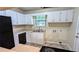 Efficient kitchen with black appliances, white cabinets, laminate countertops, and natural light at 5517 Green Wing Ct, Lithonia, GA 30058