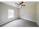 Carpeted bedroom featuring a ceiling fan, neutral walls, and a large window at 96 Lexie Ct, Rockmart, GA 30153