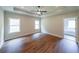 Main bedroom with tray ceiling, ceiling fan, wood-look floors, and access to the main bathroom at 96 Lexie Ct, Rockmart, GA 30153
