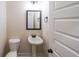 A powder room with a pedestal sink, toilet, mirror, and white trim, illuminated by modern lighting at 96 Lexie Ct, Rockmart, GA 30153