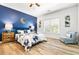 Stylish bedroom featuring a blue accent wall, a bed with decorative pillows, hardwood floors, and natural light from the window at 4670 Hamden Forest Sw Dr, Atlanta, GA 30331