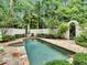 Backyard pool and spa surrounded by lush landscaping, a white wall, and an arched gate at 4670 Hamden Forest Sw Dr, Atlanta, GA 30331