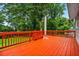 Outdoor wooden deck with red railings, and an umbrella, overlooking the backyard and trees at 5610 N Allen Rd, Mableton, GA 30126