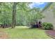 Spacious backyard with a deck area, barbecue, and a lush green lawn surrounded by trees at 3028 Towneside Ln, Woodstock, GA 30189