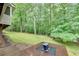 Backyard featuring a lush green lawn, wooded area, and an outdoor deck with a built-in fire pit at 3028 Towneside Ln, Woodstock, GA 30189