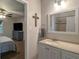 En suite bathroom with single sink vanity, framed mirror and a view into the Primary bedroom at 4409 Woodward Mill Rd, Sugar Hill, GA 30518