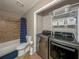 Bathroom with shower/tub combo, toilet, and laundry area with shelving at 4409 Woodward Mill Rd, Sugar Hill, GA 30518