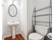 Cozy half bathroom featuring a pedestal sink, a toilet and a storage rack, all complemented by hardwood flooring at 2545 Gatewater Ct, Cumming, GA 30040