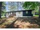 Ranch style home exterior with white painted brick and dark blue siding nestled among mature trees at 2975 Rollingwood Se Ln, Atlanta, GA 30316
