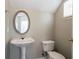 Compact half bath featuring a pedestal sink, toilet, and oval mirror over the sink at 4567 Parkway Cir, Atlanta, GA 30349