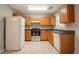 Functional kitchen with oak cabinetry, white appliances, and tile flooring at 7070 Ravenwood Ln, Lithonia, GA 30038