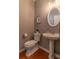 Well-lit half bathroom featuring hardwood floors, a pedestal sink, and a framed oval mirror at 939 Bendleton Dr, Woodstock, GA 30188