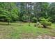 A lush green backyard is surrounded by mature trees, with a rock patio area perfect for relaxation at 1185 Wedgefield Sw Dr, Marietta, GA 30064
