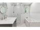 Bathroom featuring a glass-enclosed shower, soaking tub, and a round decorative mirror at 1382 6Th Ave, Auburn, GA 30011