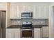 Kitchen with stainless steel appliances, granite countertops, tile backsplash, and white cabinets at 1382 6Th Ave, Auburn, GA 30011