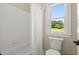 Bright bathroom featuring white tiled walls, bathtub, and a window offering natural light and a toilet at 411 Hickory Fairway Ct, Woodstock, GA 30188