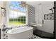 Modern bathroom features a glass enclosed shower and soaking tub beneath an arched window at 411 Hickory Fairway Ct, Woodstock, GA 30188