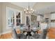 Charming dining area featuring a glass table and seating for four, illuminated by a chandelier and natural light at 411 Hickory Fairway Ct, Woodstock, GA 30188