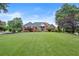 Traditional brick home with manicured lawn and mature landscaping including trees and trimmed bushes at 411 Hickory Fairway Ct, Woodstock, GA 30188
