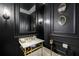 Stylish powder room with black walls, gold fixtures, marble countertop, and decorative mirrors at 816 Blackfoot Trl, Suwanee, GA 30024