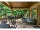 Covered outdoor patio with stone flooring, featuring comfortable seating and views of the lush backyard at 816 Blackfoot Trl, Suwanee, GA 30024