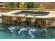 Luxurious pool and spa with stone accents and cascading waterfalls for a relaxing and tranquil backyard experience at 816 Blackfoot Trl, Suwanee, GA 30024