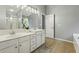 Bathroom with double sinks, white cabinets, and neutral tile at 3395 The Commons Dr, Cumming, GA 30041