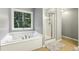 Bright bathroom featuring a soaking tub under a window and a glass-enclosed shower at 3395 The Commons Dr, Cumming, GA 30041