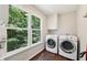Bright laundry room features a washer, dryer, built-in storage and a window overlooking the wooded backyard at 4733 Eidson Road, Dunwoody, GA 30360