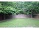 Lush green backyard with mature trees and a stone retaining wall offers privacy and space for outdoor enjoyment at 942 Idlewood Dr, Canton, GA 30115
