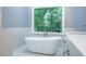 Luxurious bathroom with a freestanding soaking tub and a large window overlooking the trees at 3924 Ashford Dunwoody Road Northeast Ne Rd, Atlanta, GA 30319