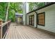 Rear exterior view of home featuring a spacious wooden deck, black windows, and a lush tree canopy at 3924 Ashford Dunwoody Road Northeast Ne Rd, Atlanta, GA 30319