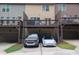 Rear view of home with deck above garages and parking, with a pair of vehicles at 3937 Covey Flush Sw Ct # 25, Smyrna, GA 30082