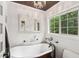 Bright bathroom showcasing a soaking tub, wainscoting, and a window with green views at 10875 Shagbark Trl, Roswell, GA 30075