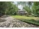 Scenic view of a charming two-story home with a covered front porch, deck, and expansive lawn surrounded by trees at 10875 Shagbark Trl, Roswell, GA 30075
