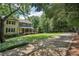 Quaint two-story home with a covered front porch, landscaped yard, and mature trees along a long driveway at 10875 Shagbark Trl, Roswell, GA 30075