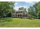 Beautiful two-story home featuring a covered front porch, deck, and well-manicured lawn with mature trees at 10875 Shagbark Trl, Roswell, GA 30075
